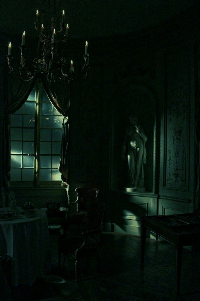 a dark room with a chandelier and table