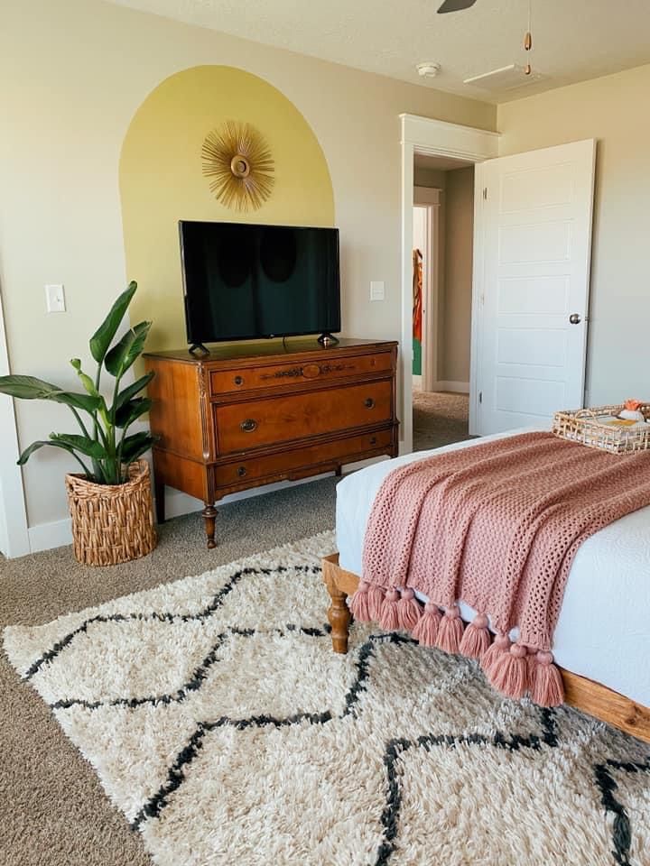 a bedroom with a bed, dresser and flat screen tv on top of the wall