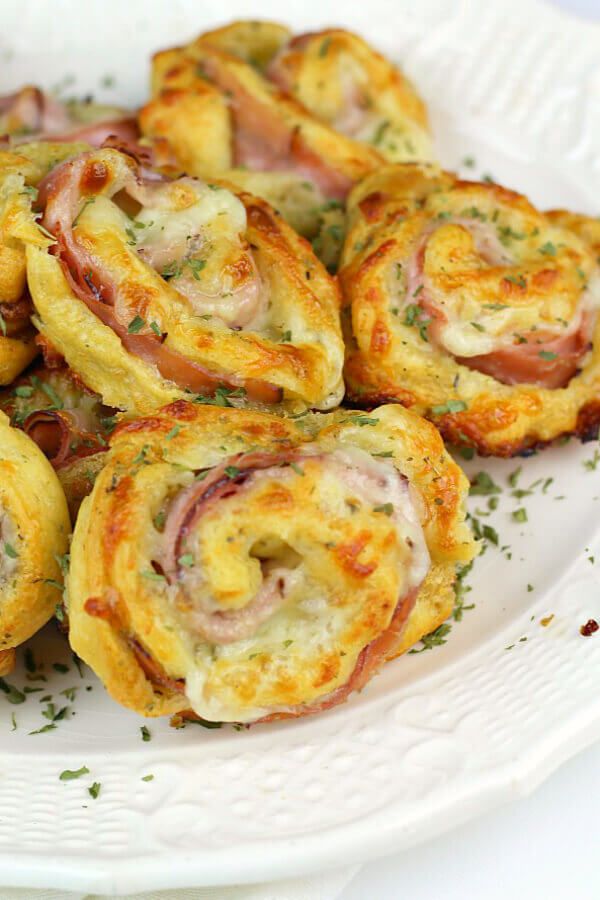 ham and cheese rolls on a white plate with garnishes around the edges