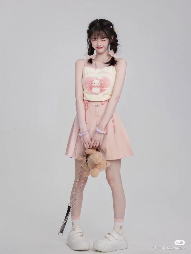 a young woman holding a teddy bear and wearing a pink skirt with white shoes on her feet