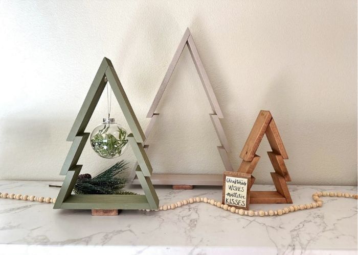 three wooden christmas trees sitting on top of a white marble counter next to each other