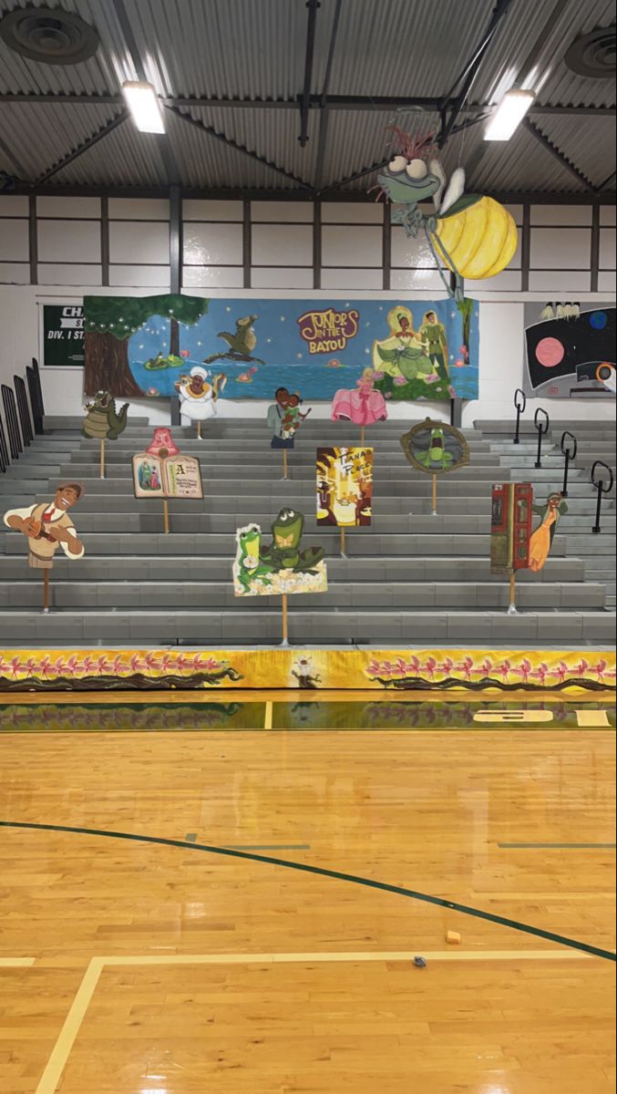 an empty gym with wooden flooring and painted banners on the sidelines for sports teams