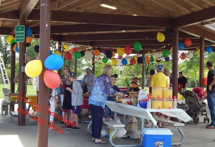 people are standing under a covered area with balloons