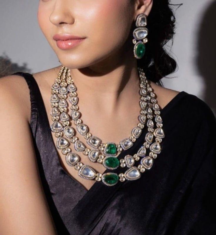 Elevate your elegance with this exquisite Sabyasachi-inspired three-layered necklace set, meticulously crafted to captivate and charm. The necklace features three gracefully cascading layers, each adorned with lustrous, high-quality moissanite stones that shimmer with every movement. The brilliance of the moissanite stones, renowned for their fire and sparkle, is beautifully complemented by deep, rich emerald accents that add a touch of opulent color and sophistication. The intricate design pays Necklaces Styling, Emerald Necklace Set, Cord Earrings, Punjabi Jewelry, Kundan Choker, Golden Necklace, Layered Necklace Set, Moissanite Necklace, Long Necklaces