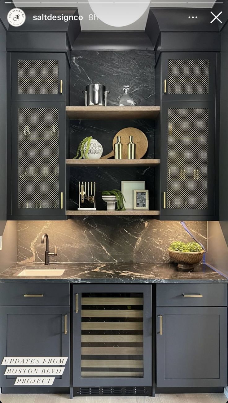 a kitchen with black cabinets and marble counter tops, gold trimmings on the doors