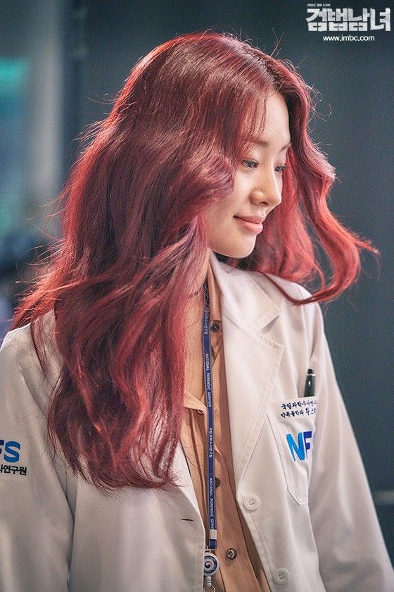 a woman with long red hair wearing a lab coat