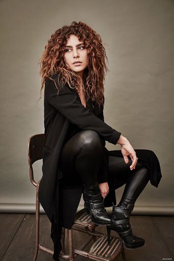 a woman sitting on top of a chair wearing black leather pants and knee high boots