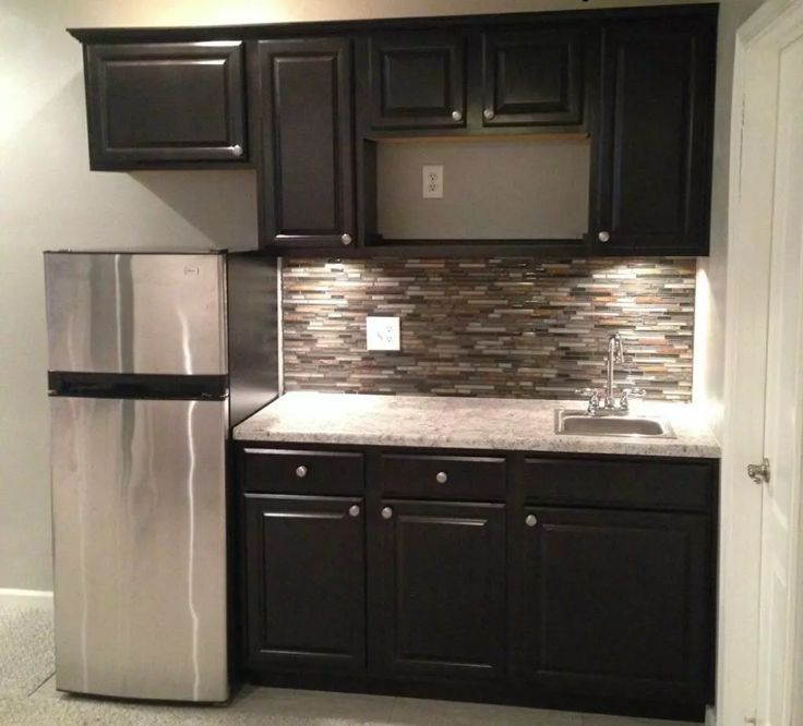 a kitchen with black cabinets and silver appliances