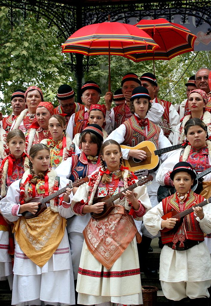 a group of people standing next to each other in front of a red and white umbrella