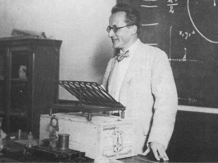 an old black and white photo of a man standing in front of a box with magnets on it