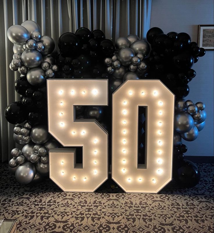 the number 50 is lit up in front of balloons