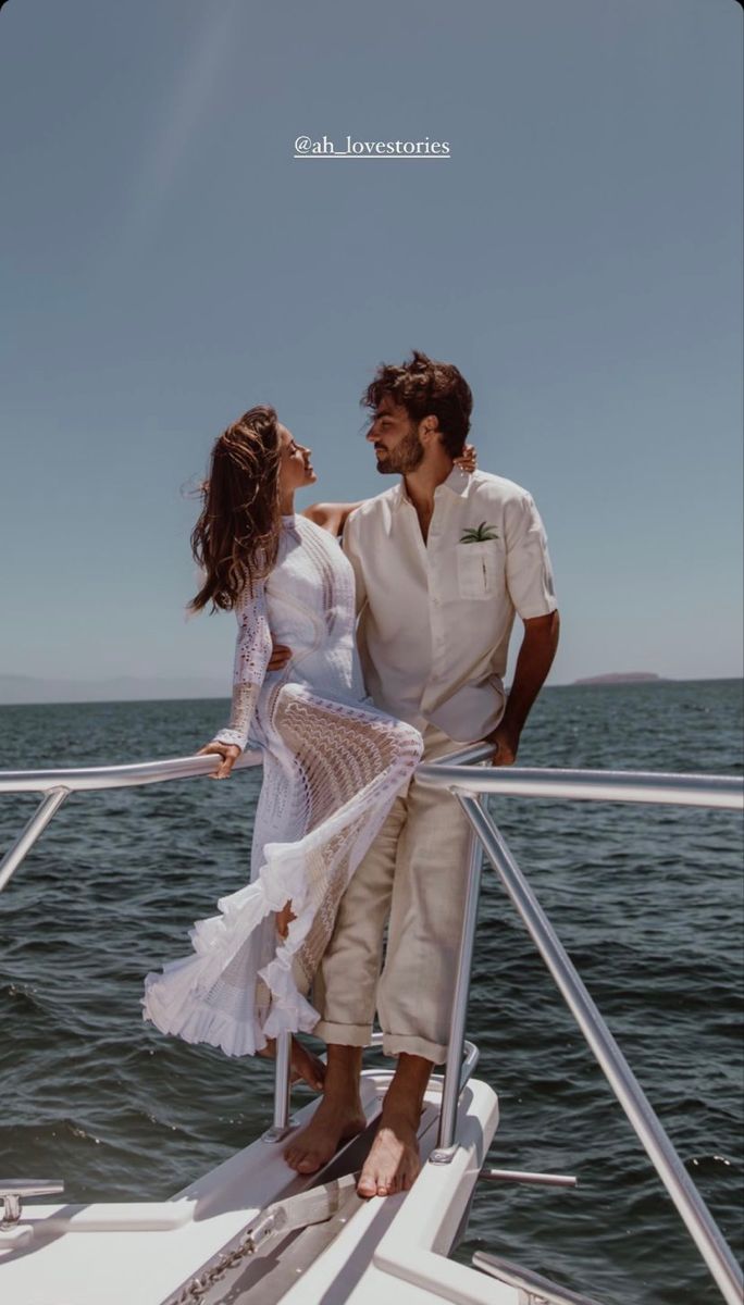 a man and woman standing on the back of a boat in front of the ocean