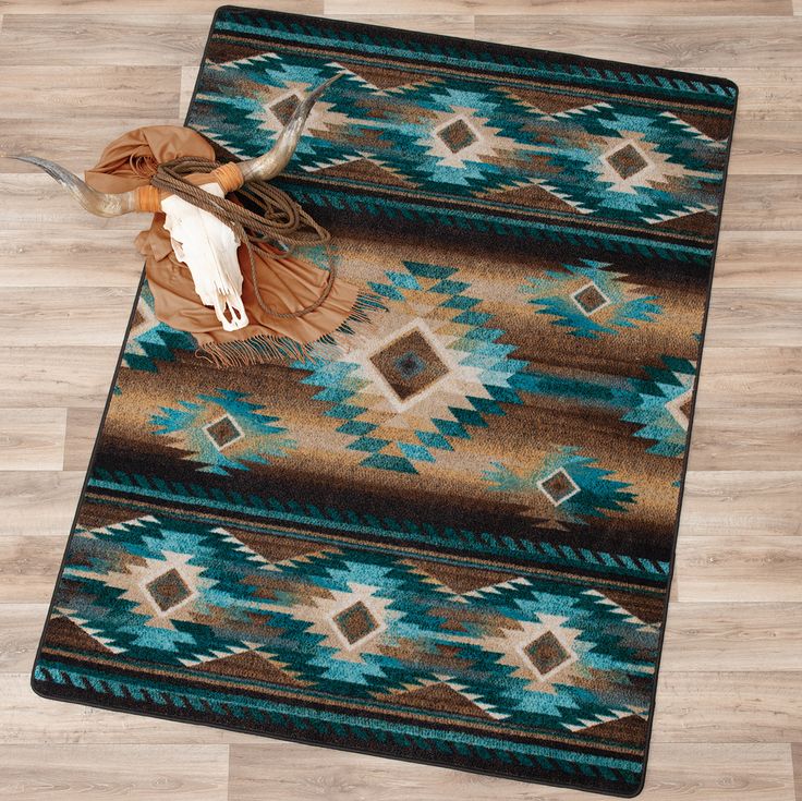 an area rug with a cow skull on the top and turquoise, brown, and tan colors