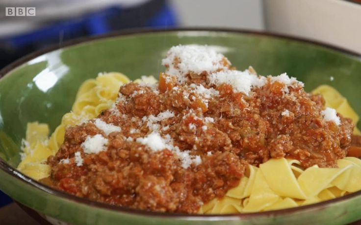 a green bowl filled with pasta and sauce