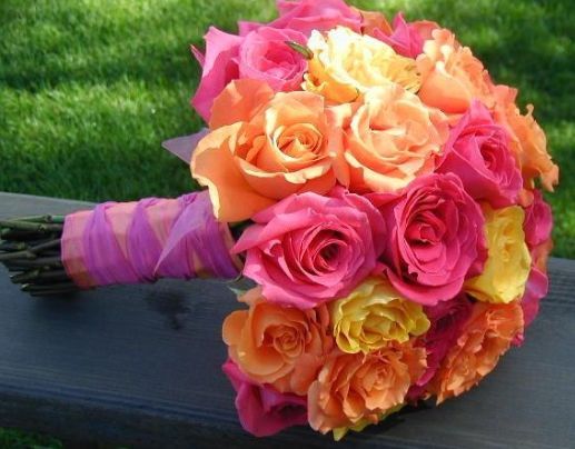 an orange and pink bouquet sitting on top of a bench