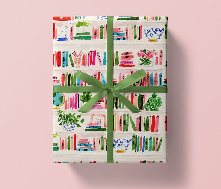 a present wrapped in wrapping paper with a green bow on it and bookshelves