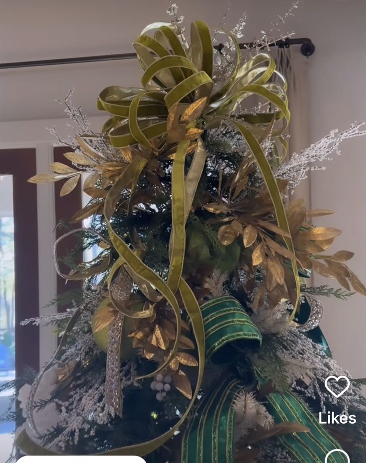 a christmas tree decorated with gold and green ribbons