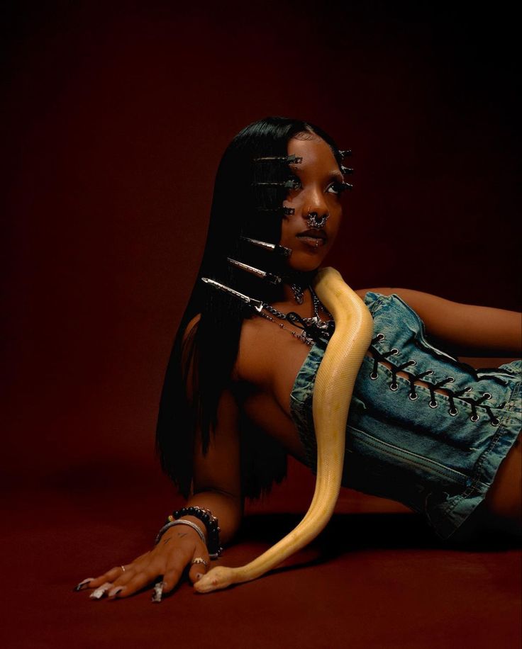 a woman with long hair and piercings sitting on the ground