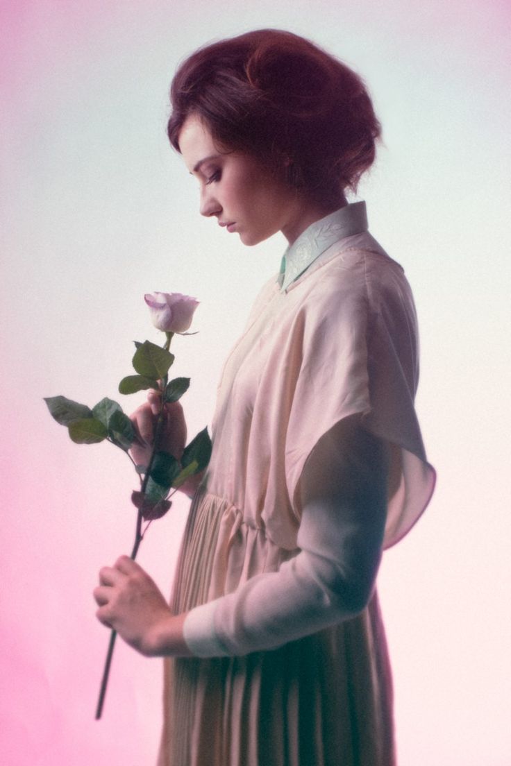 a woman is holding a rose in her hand