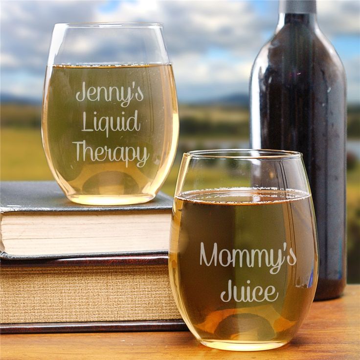 two wine glasses sitting on top of a wooden table next to a book and bottle