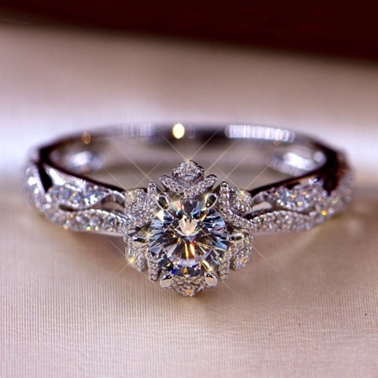 a diamond ring is sitting on top of a white cloth with the center stone surrounded by smaller diamonds