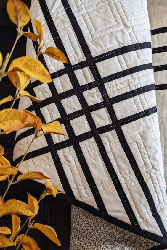 two black and white quilts are next to each other on a table with a plant