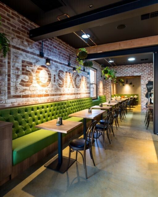 an empty restaurant with green booths and brick walls