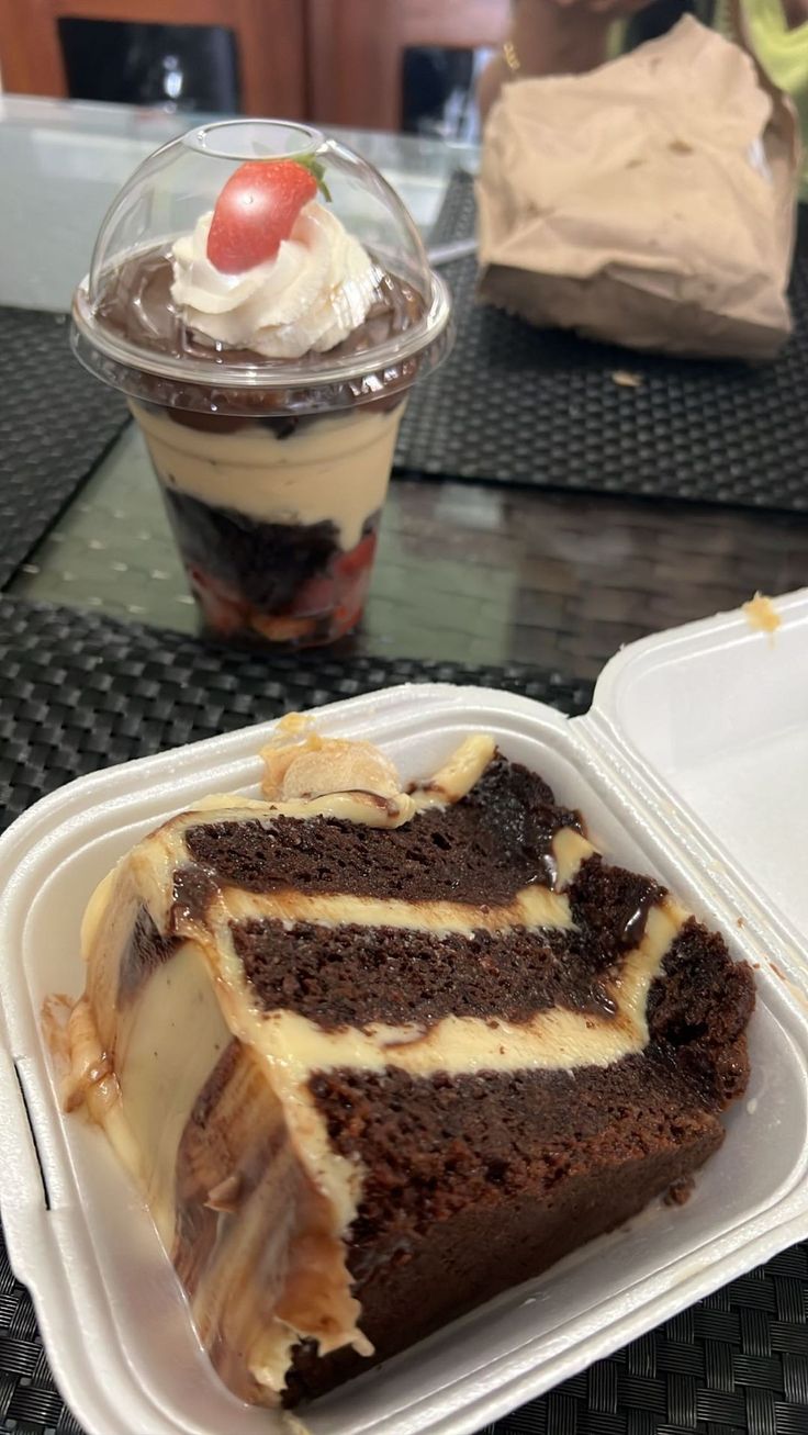 a piece of chocolate cake and ice cream in a take out container on a table