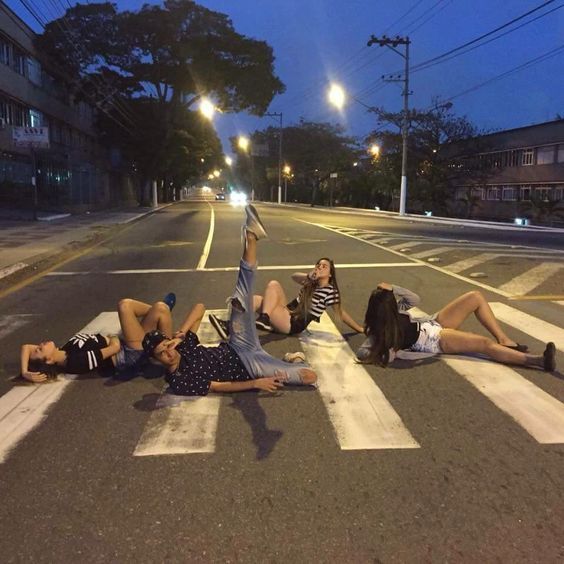 three people laying on the crosswalk at night with their feet up in the air