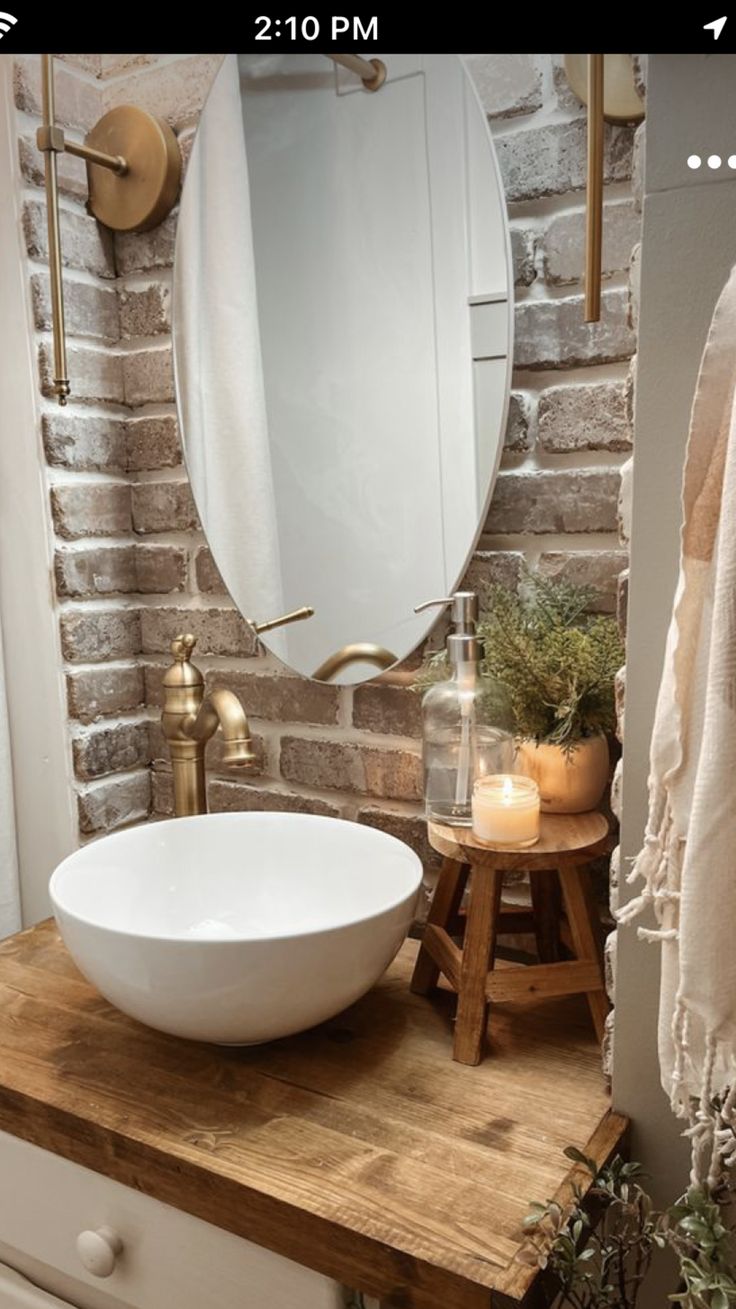 a white bowl sink sitting on top of a wooden counter next to a brick wall