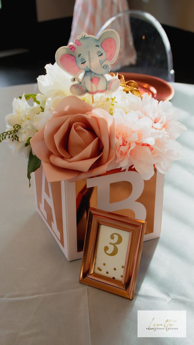 an elephant figurine sitting on top of a box filled with flowers