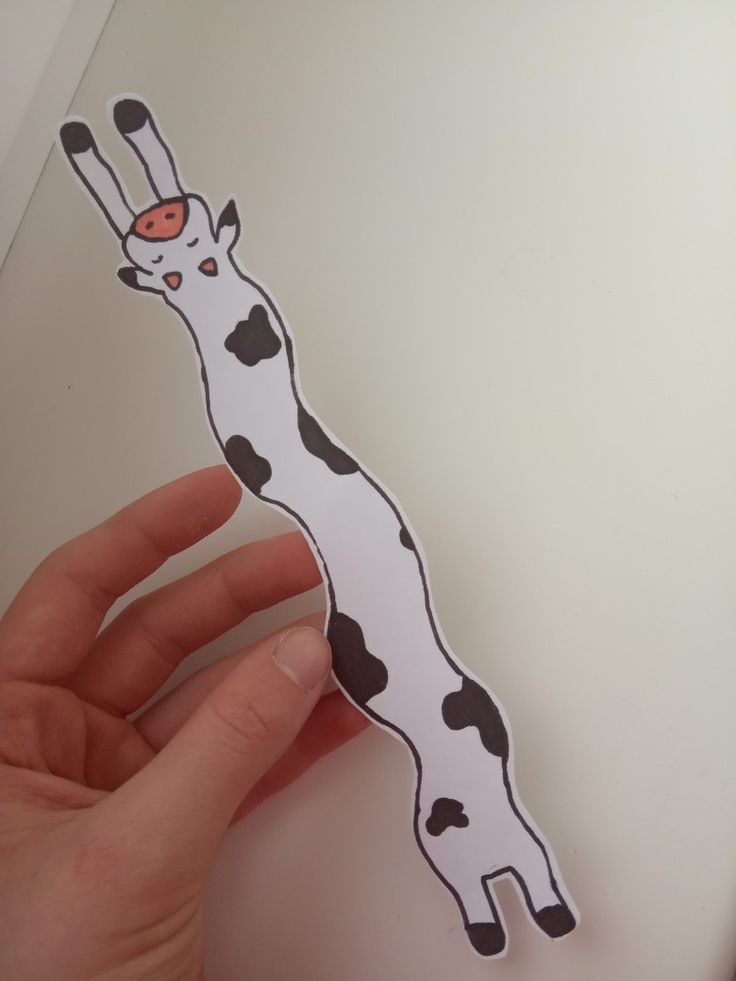 a hand holding up a piece of paper with a sticker of a giraffe on it