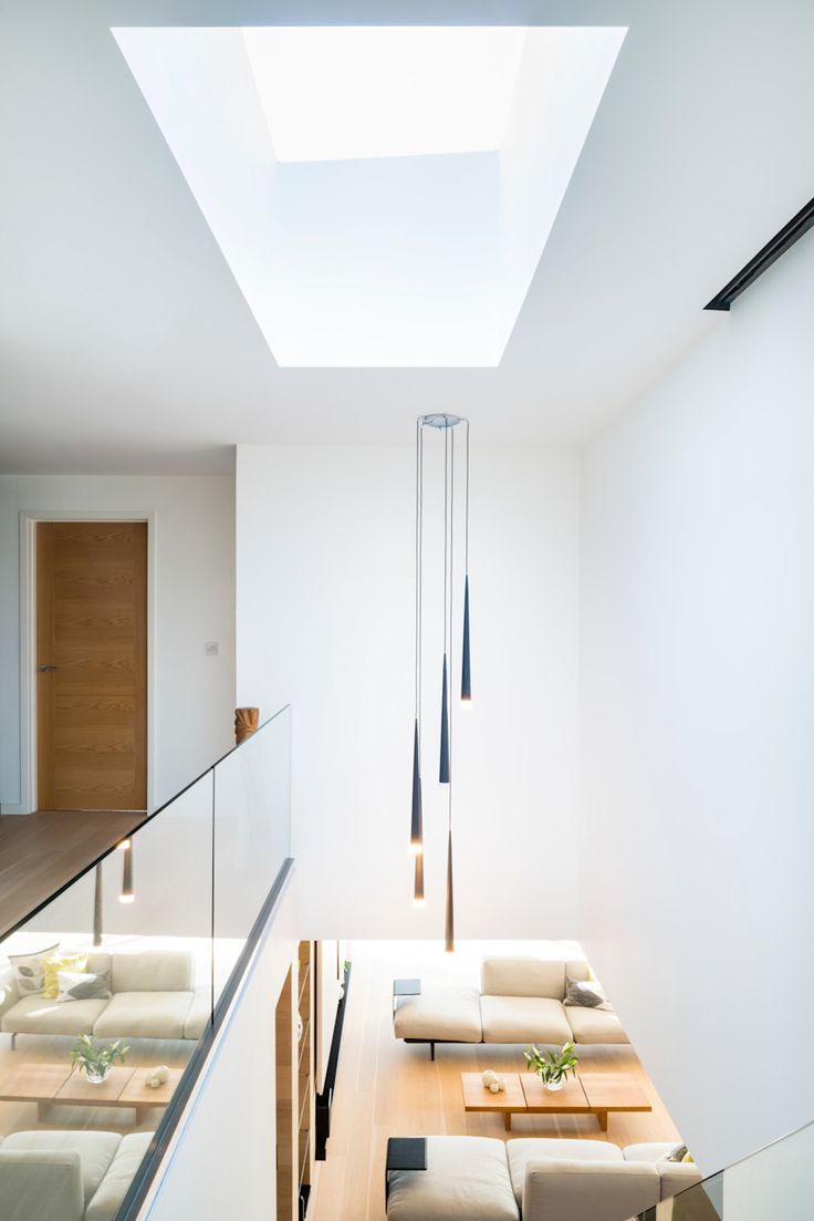 a living room filled with lots of furniture under a skylight next to a stair case