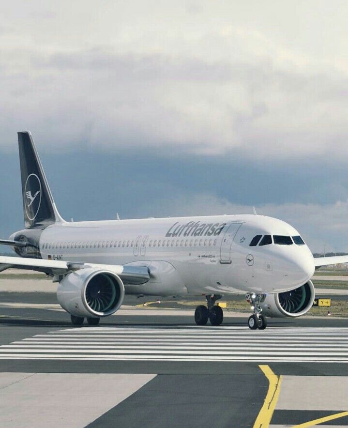 a large jetliner sitting on top of an airport tarmac with clouds in the background