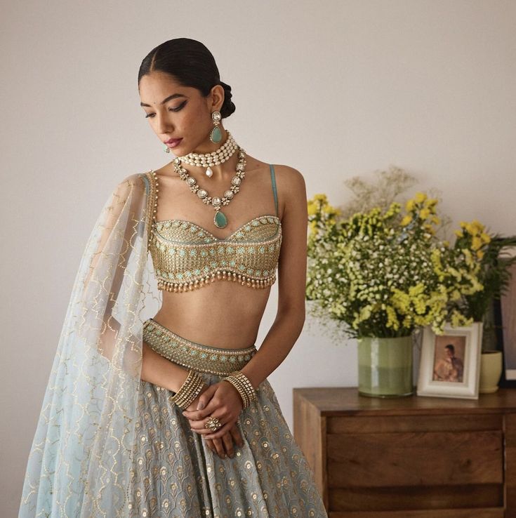 a woman in a blue lehenga and matching necklaces is posing for the camera