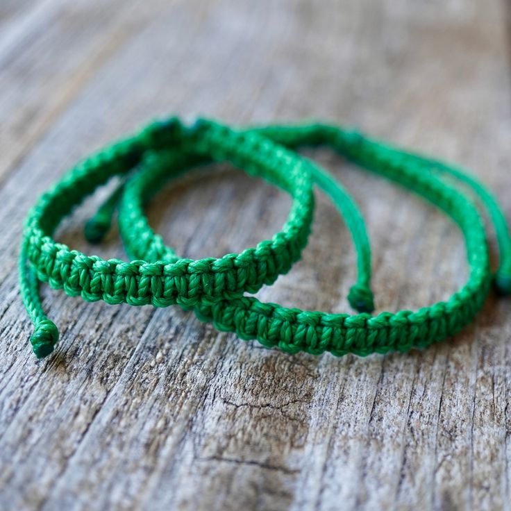 two green bracelets sitting on top of a wooden table