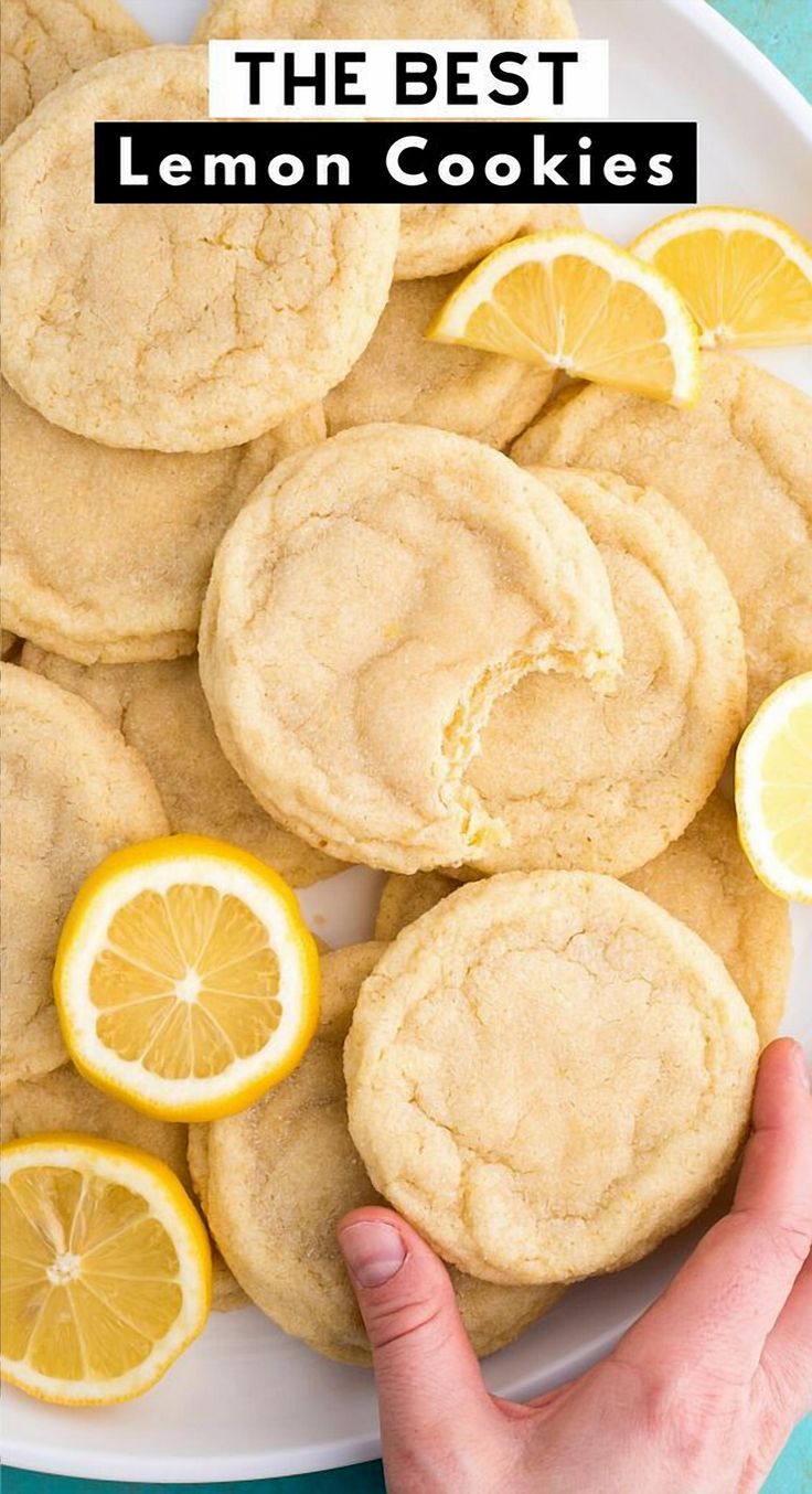 the best lemon cookies on a white plate with sliced lemons and one being held up by a hand