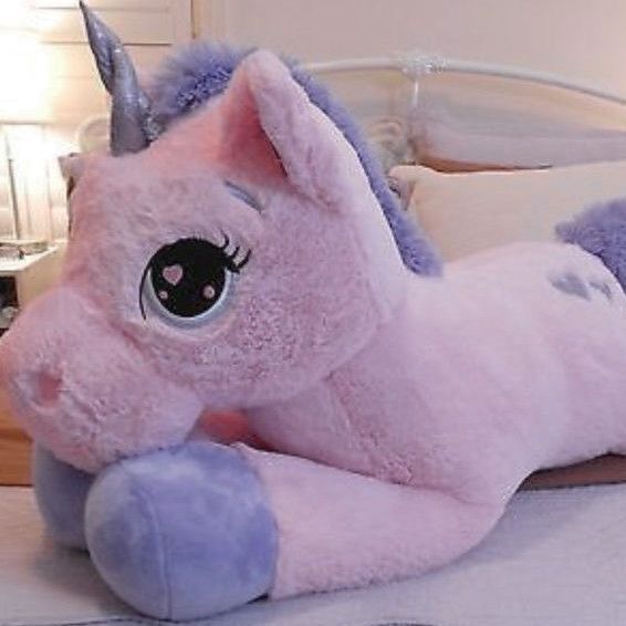 a pink stuffed unicorn laying on top of a bed