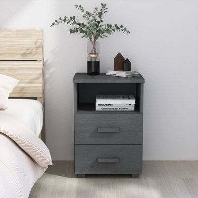 a nightstand with two drawers next to a bed and a plant on top of it