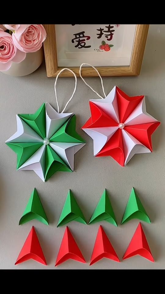 four origami stars are arranged on a table next to flowers and a framed picture