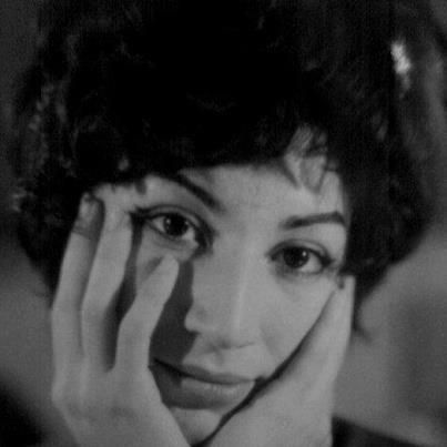 a black and white photo of a woman holding her hands to her face while looking at the camera