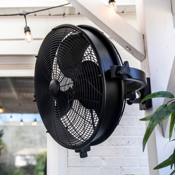 a black fan hanging from the side of a building