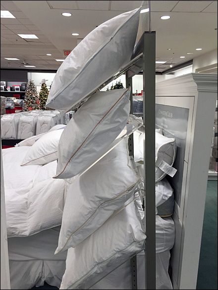 a pile of white pillows sitting on top of a shelf