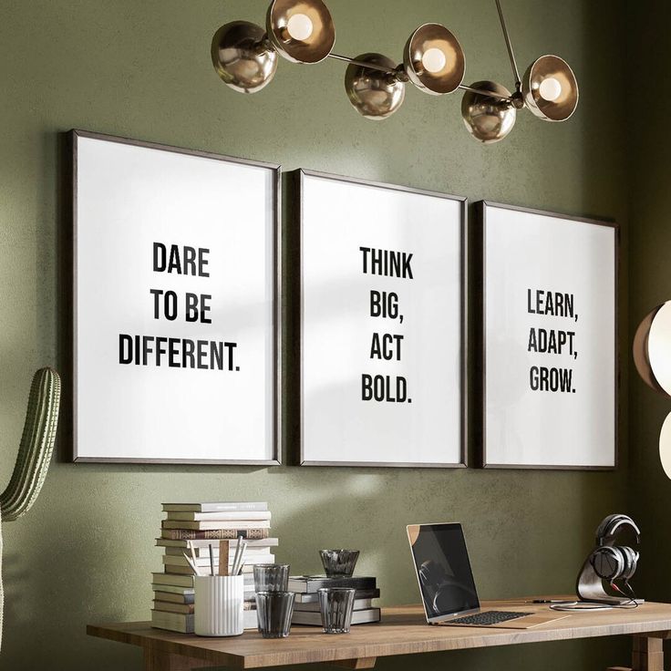 three posters hanging on the wall above a desk with a laptop computer and other items