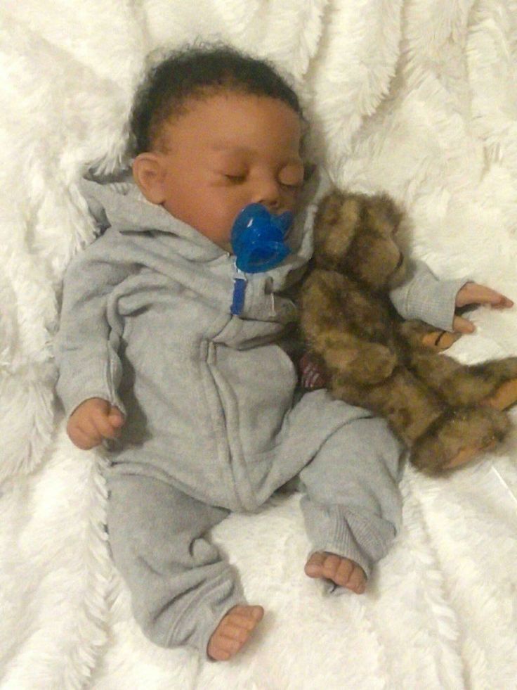 a baby is laying down with a stuffed teddy bear in his mouth and wearing a pacifier