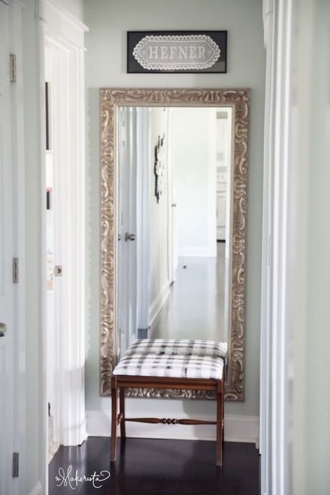 a mirror sitting on top of a wooden bench in front of a doorway with a sign above it