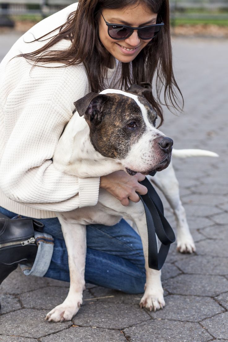 a woman kneeling down holding a dog in her lap