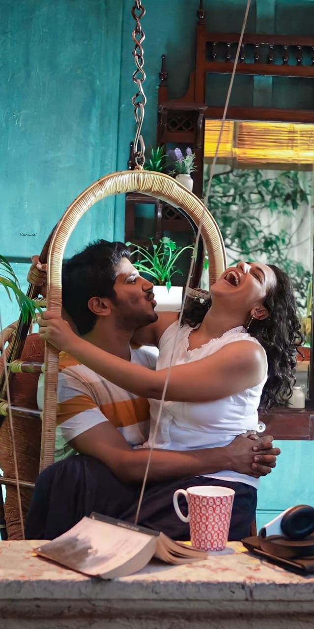 a man and woman are sitting in a hammock with their arms around each other