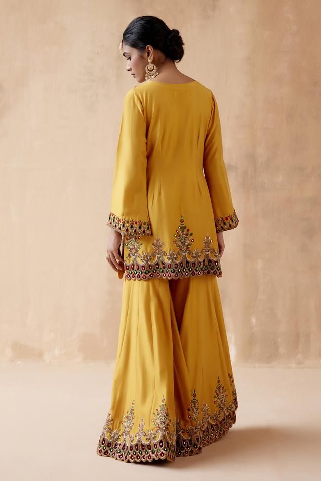 Mustard kurta with velvet patchwork, mirror, pearl, bead, thread embroidery on yoke and hem. Paired with sharara and dupatta.
Components: 3
Pattern: Embroidery
Type Of Work: Velvet patchwork, Mirror, Pearl, Bead, Thread
Neckline: V neck
Sleeve Type: Bell sleeves
Fabric: Dupion Silk, Organza
Color: Yellow
Other Details: 
Scallop hem
Tassel bordered dupatta
Model height: 5ft 9inches, wearing size S
Occasion: Sangeet - Aza Fashions Marriage Suit, Embroidery Kurta, Velvet Patchwork, Kurta Sharara Set, Satin Suit, Kurta Sharara, Classy Suits, Punjabi Outfits, Boutique Suits