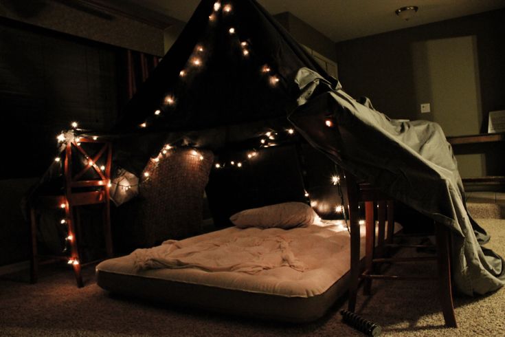 a bed that has some lights on the side of it and is in a dark room